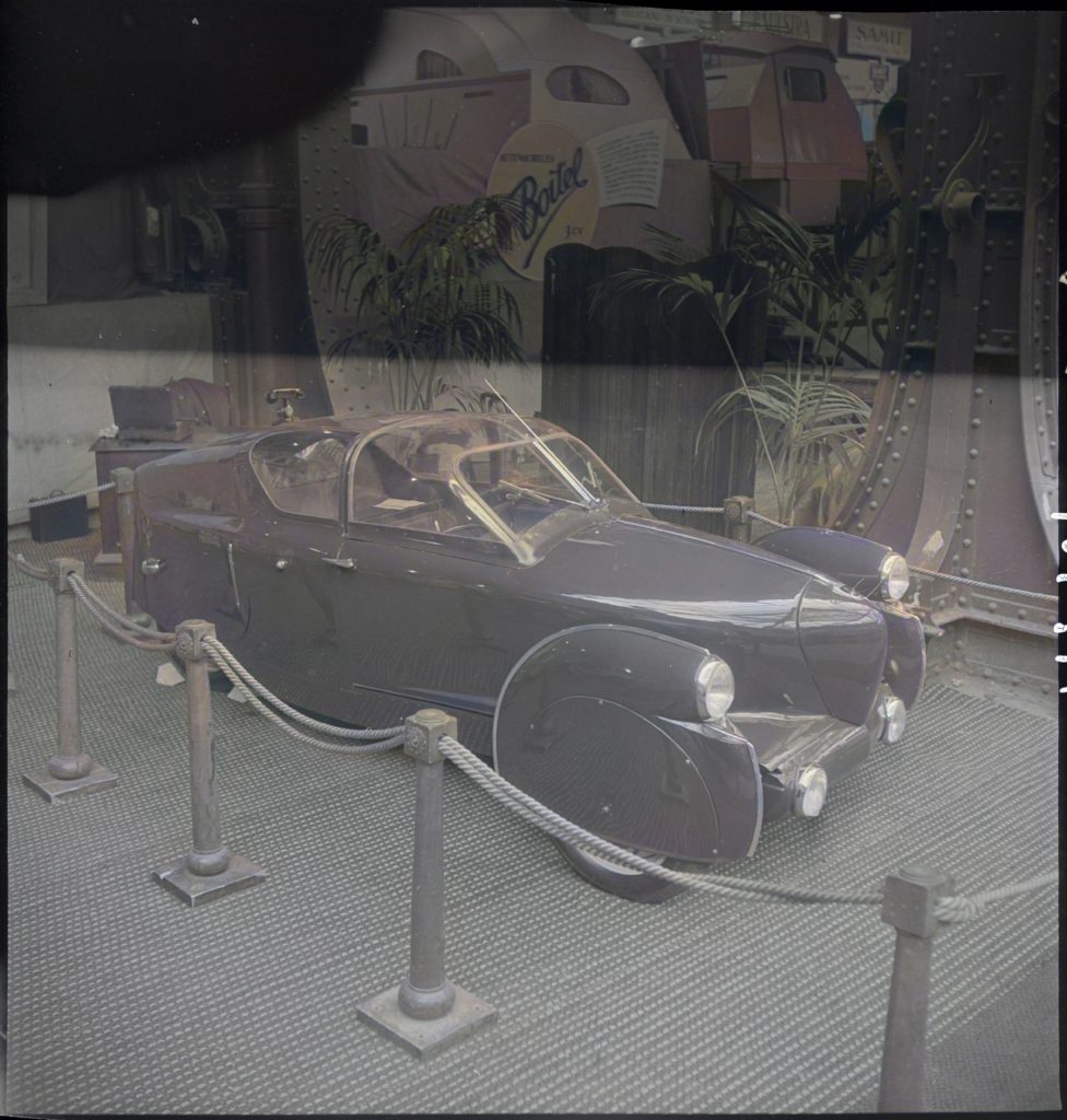 Photo colorisée de l'Aérocarène 700 lors du salon 1947 au Grand Palais à Paris. La voiture arbore une couleur bleu roi magnifique!